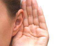 zdjecie kobiecego ucha z przyłożną dłonią w geście nasłuchiwania